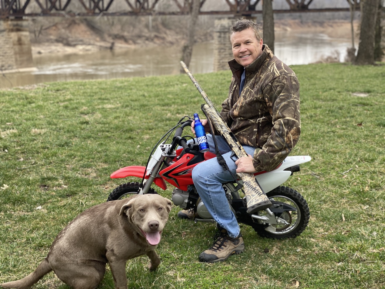 Man with his dog on a minibike by the river